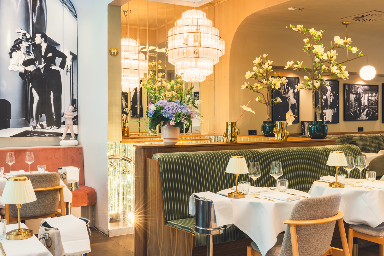 Warm evening bar atmosphere at Casa Bellucci with crystal chandelier, green velvet bench and counter in Berlin-Charlottenburg